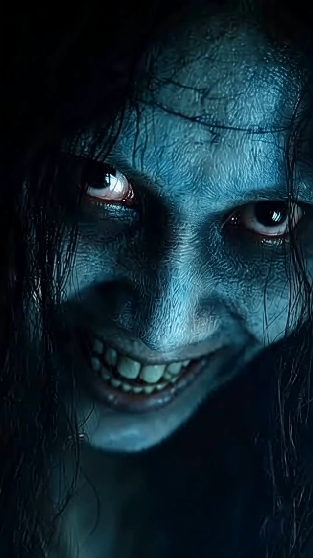 The person slowly tilts their head further to the right, their wide, unsettling grin becoming more pronounced as they l…